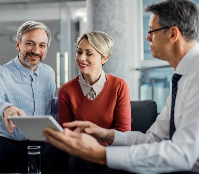 happy-mid-adult-couple-using-touchpad-with-their-financial-consultant-in-the-office-1.jpg